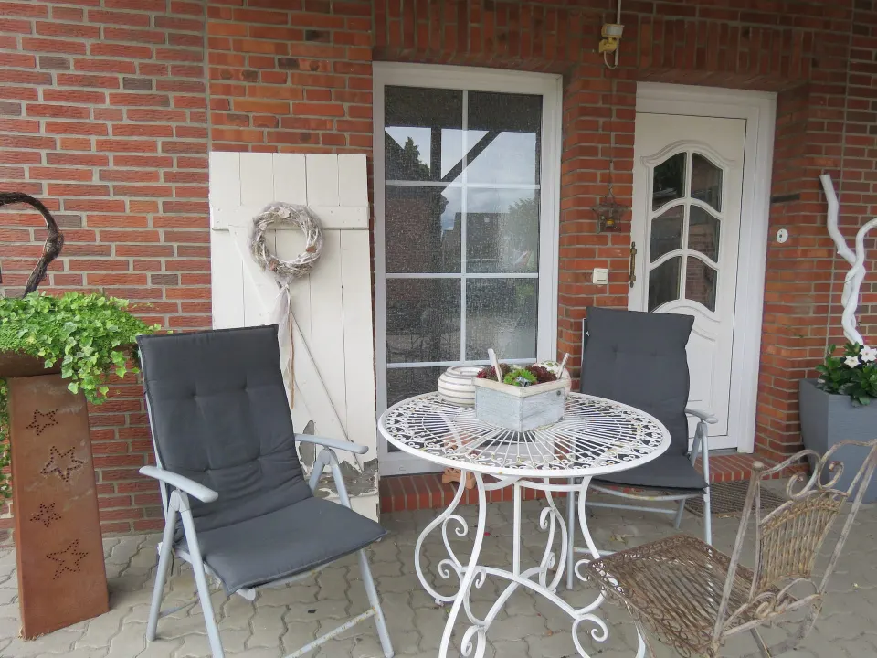 Terrasse mit Gartenstühlen und Tisch vor der Backsteinfassade des Hauses