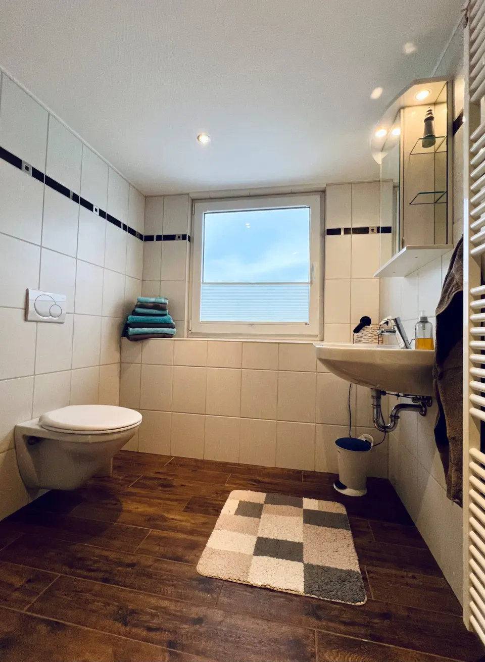 Badezimmer mit Fenster, WC und weißen Fliesen