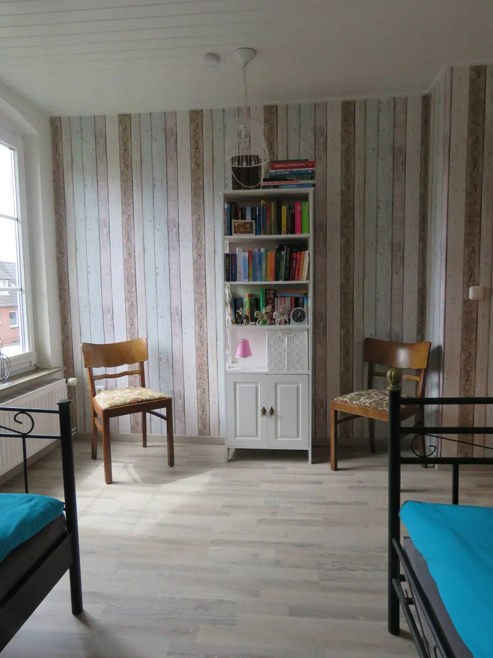 Zweites Schlafzimmer mit Bücherregal, Stühlen und Tapete